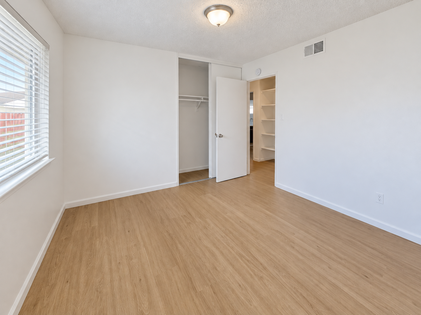 Bright unfurnished bedroom with window and closet shelving